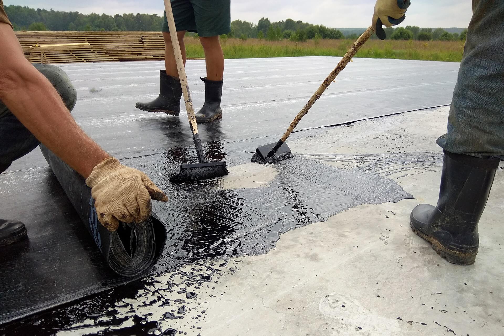roofer-worker-painting-bitumen-praimer-concrete-surface-by-roller-brush-waterproofing